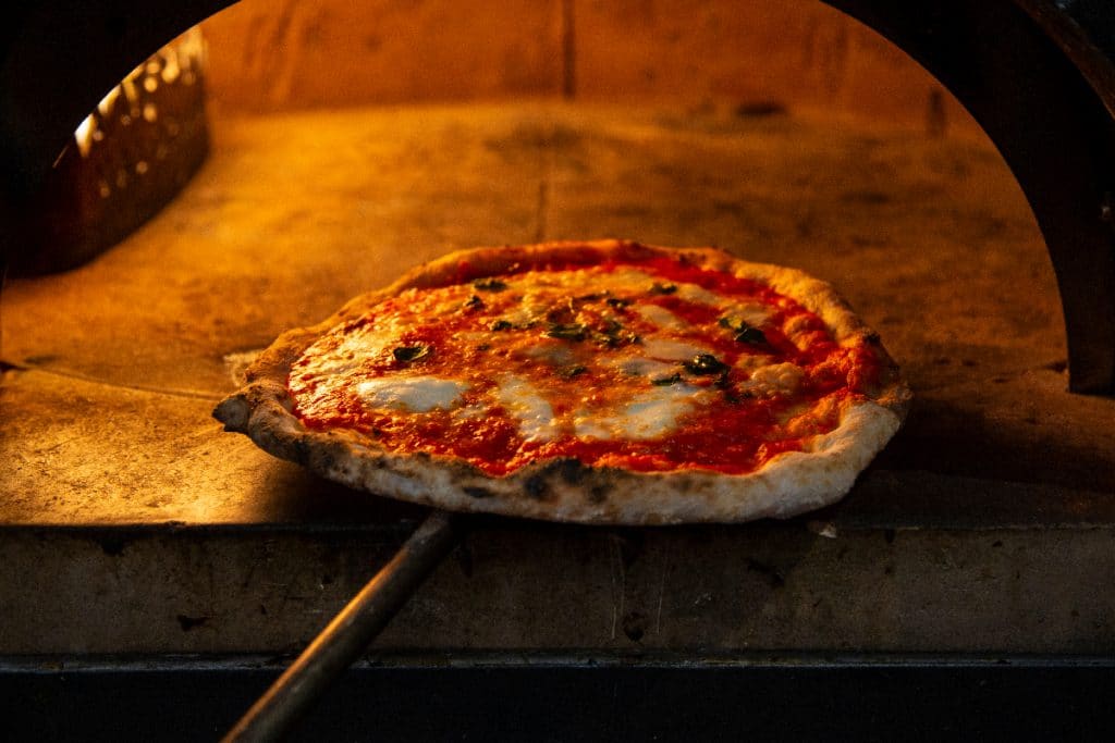 Pizza napolitana saliendo del horno de piedra.